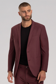 A man with a close-cropped beard and buzz cut wears the Twillory AIR Blazer in Burgundy, paired with matching pants and a black crew-neck shirt. He looks slightly left with a neutral expression against a plain light gray background.