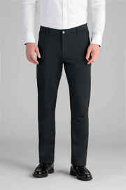 A person models the Performance Pants // BLACK with a white button-up shirt and black dress shoes, standing against a plain gray background. The photo is taken from shoulders to feet.