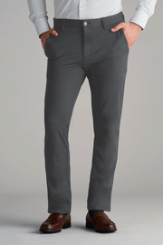 A person models Twillory Performance Pants in SLATE GREY with a light shirt and brown dress shoes, hands in pockets. The shot is cropped mid-torso to feet against a plain light gray background.