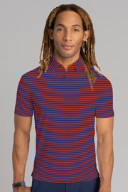 A person with long, light brown dreadlocks and light skin wears the Twillory Short Sleeve Polo Stripe in Red Blue. They face forward, slightly smiling, with a dark wristwatch on their left wrist against a plain light gray background.