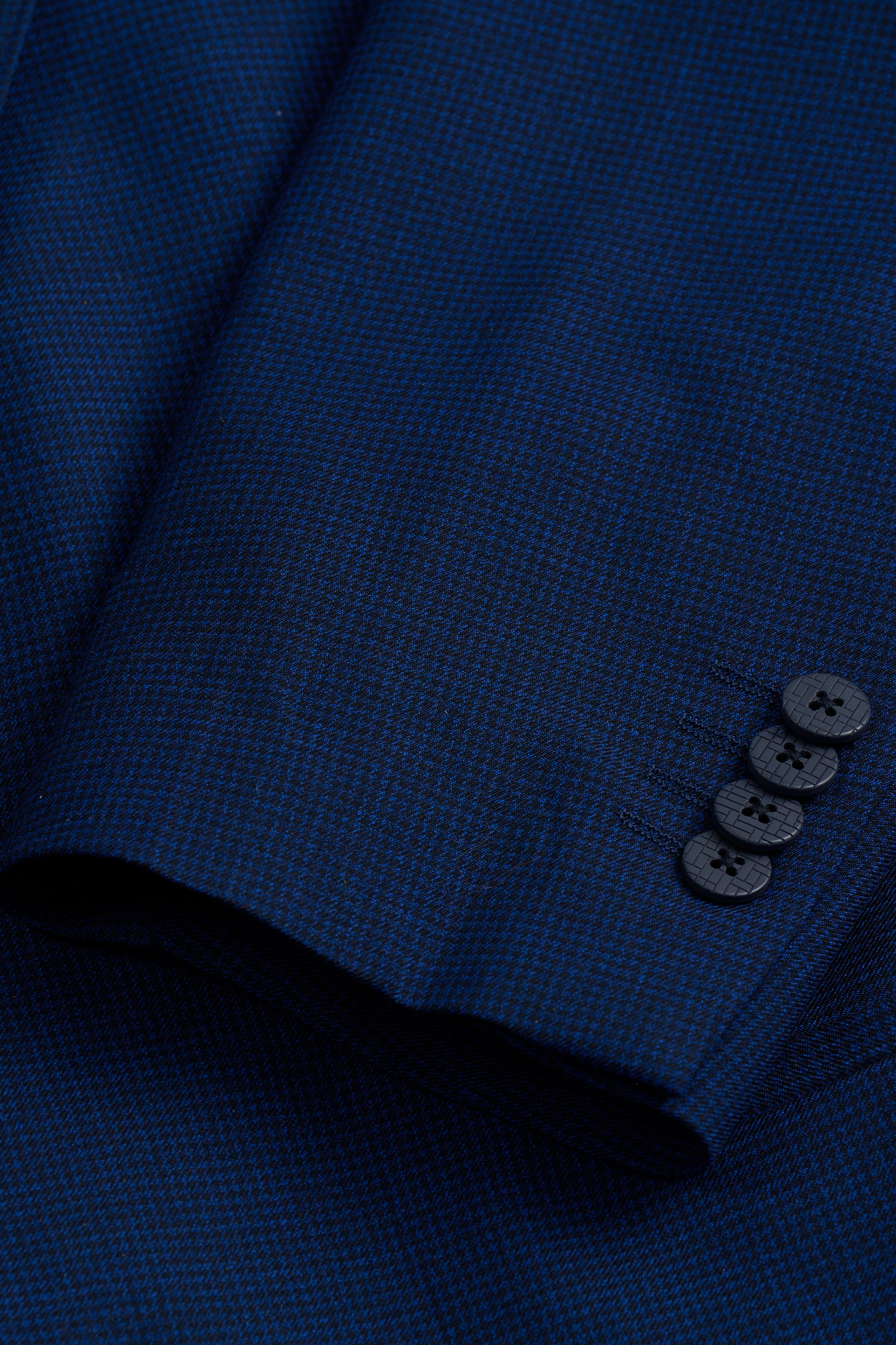 Close-up of the Twillory Hybrid Wool Blazer // Navy Puppytooth sleeve, showcasing its fine puppytooth pattern and four dark cuff buttons. The fabric features 4-way stretch for comfort and ease of movement.