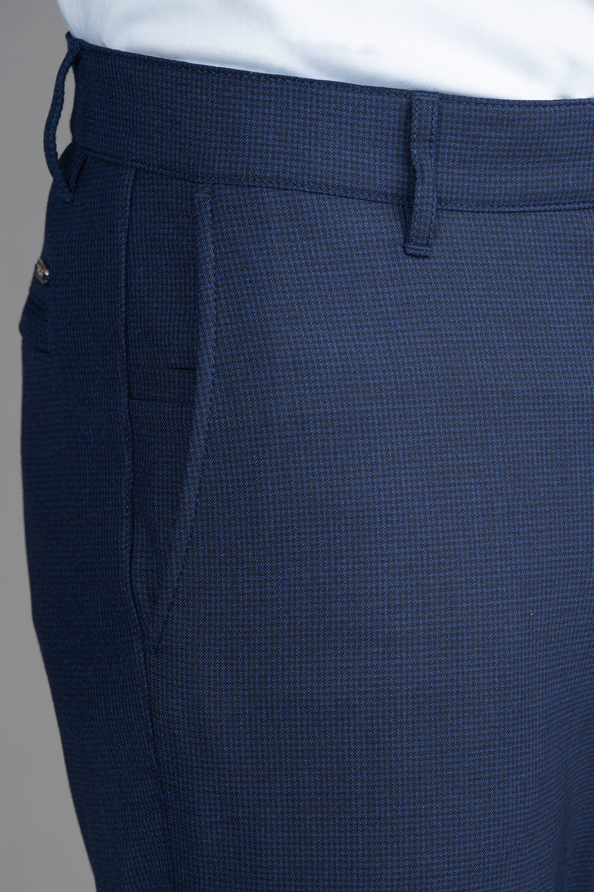 Close-up of a person wearing Twillory Hybrid Wool Pants // Navy Puppytooth, featuring 4-way stretch, front pocket, belt loops, and visible stitching and textured fabric at the waist and upper thigh. Paired with a white shirt.