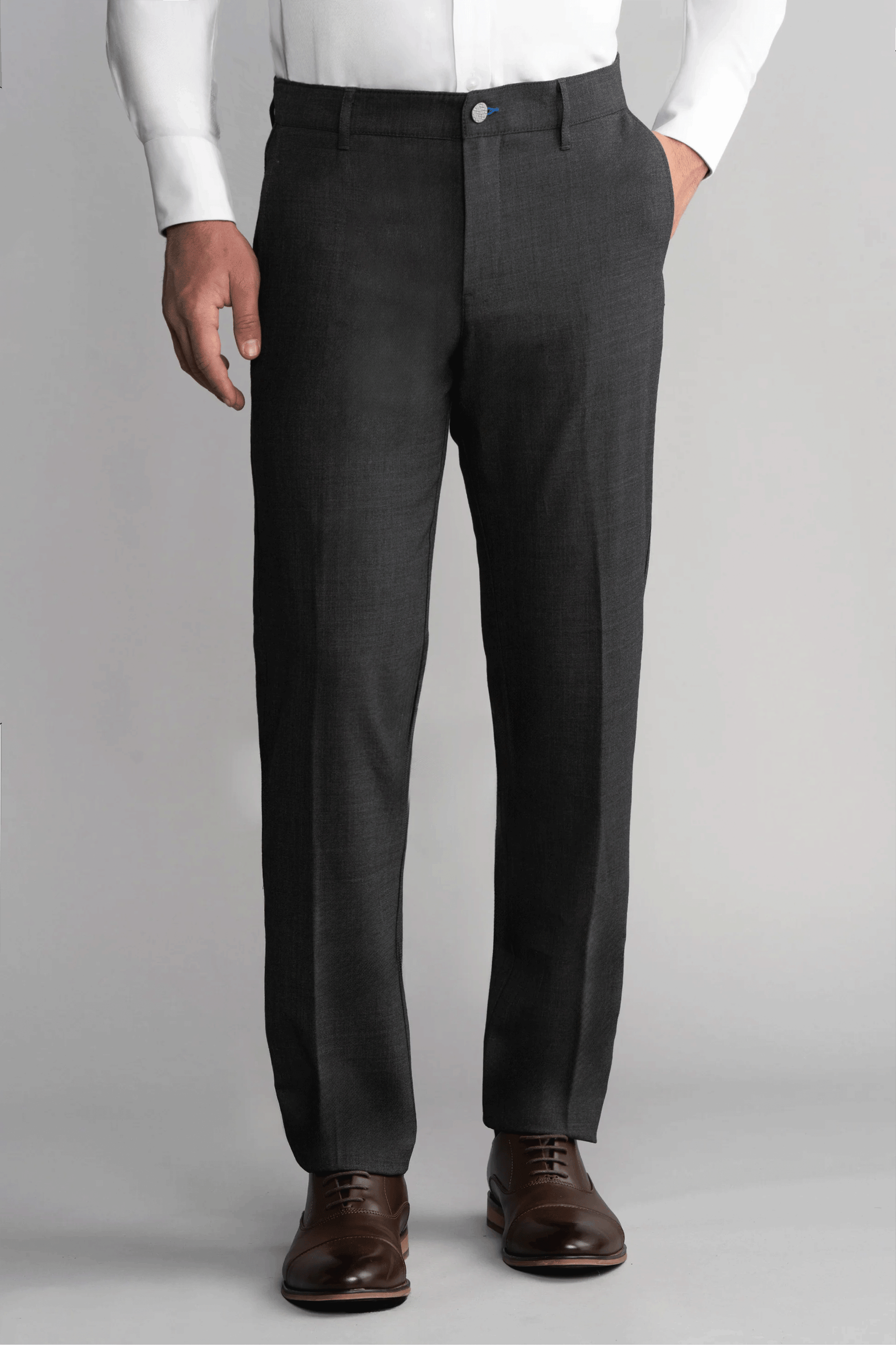 A man stands against a plain gray background wearing Twillory Hybrid Wool Pants in Grey Heather. His left hand is in his pocket, right arm by his side, and the image focuses on his lower torso and legs.