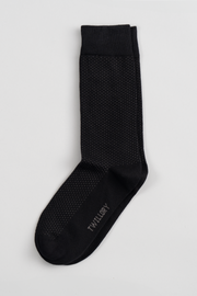 A single Twillory Black Pin Dot dress sock with small white polka dots is laid flat on a white background. The toe displays the brand name in light gray. It features a ribbed cuff and classic shape, ideal for your sock collection.