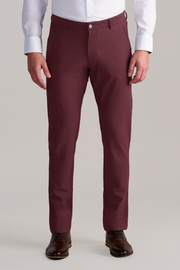 A man models the Twillory AIR Pants in Burgundy, styled with a white dress shirt and dark brown leather shoes. The photo captures him from shoulders to feet against a plain light background.