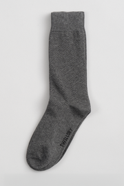 A single mid-calf Grey Pin Dot sock by Twillory lies flat on a white surface, featuring a subtle textured pattern and the Twillory logo near the toe—a top pick for comfort and quality when restocking your socks.