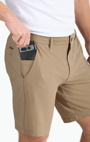Man in beige shorts placing a smartphone in the pocket.