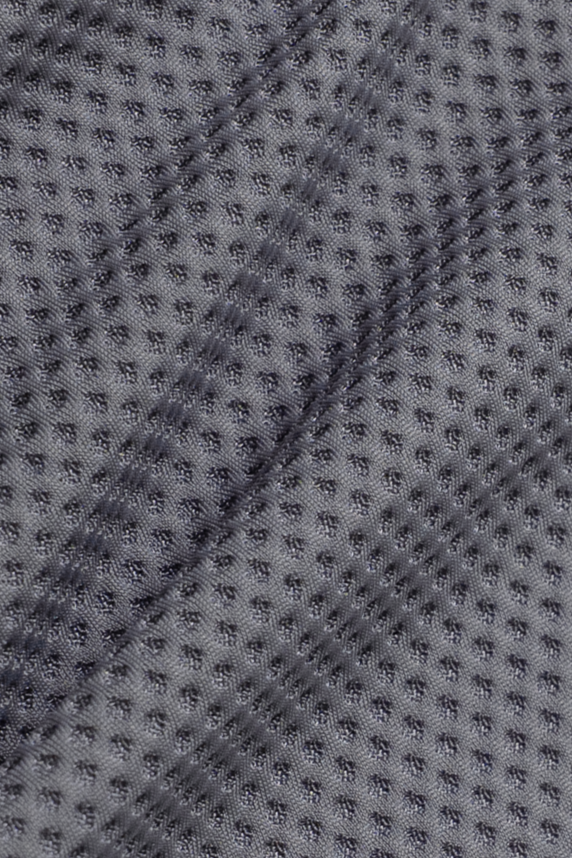 Close-up of the AIR Shorts by Twillory shows grey, sweat-wicking fabric with a grid of small raised dots. The texture and subtle wrinkles catch the light, adding depth to this high-performance design.
