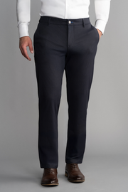 A man, shown from chest down against a gray background, wears a white long-sleeve shirt and Twillory Performance Pants in Navy Pin Stripe with hands in pockets and brown dress shoes. The look is formal and polished.