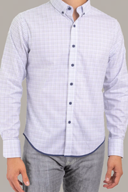 A man (face not shown) wears Twillory’s untuck(able) Tri-Blue Windowpane shirt—smart casual, long-sleeved, with dark blue buttons and gray jeans. The non-iron stretch fabric stays crisp. Shirt is untucked; background is plain light gray.