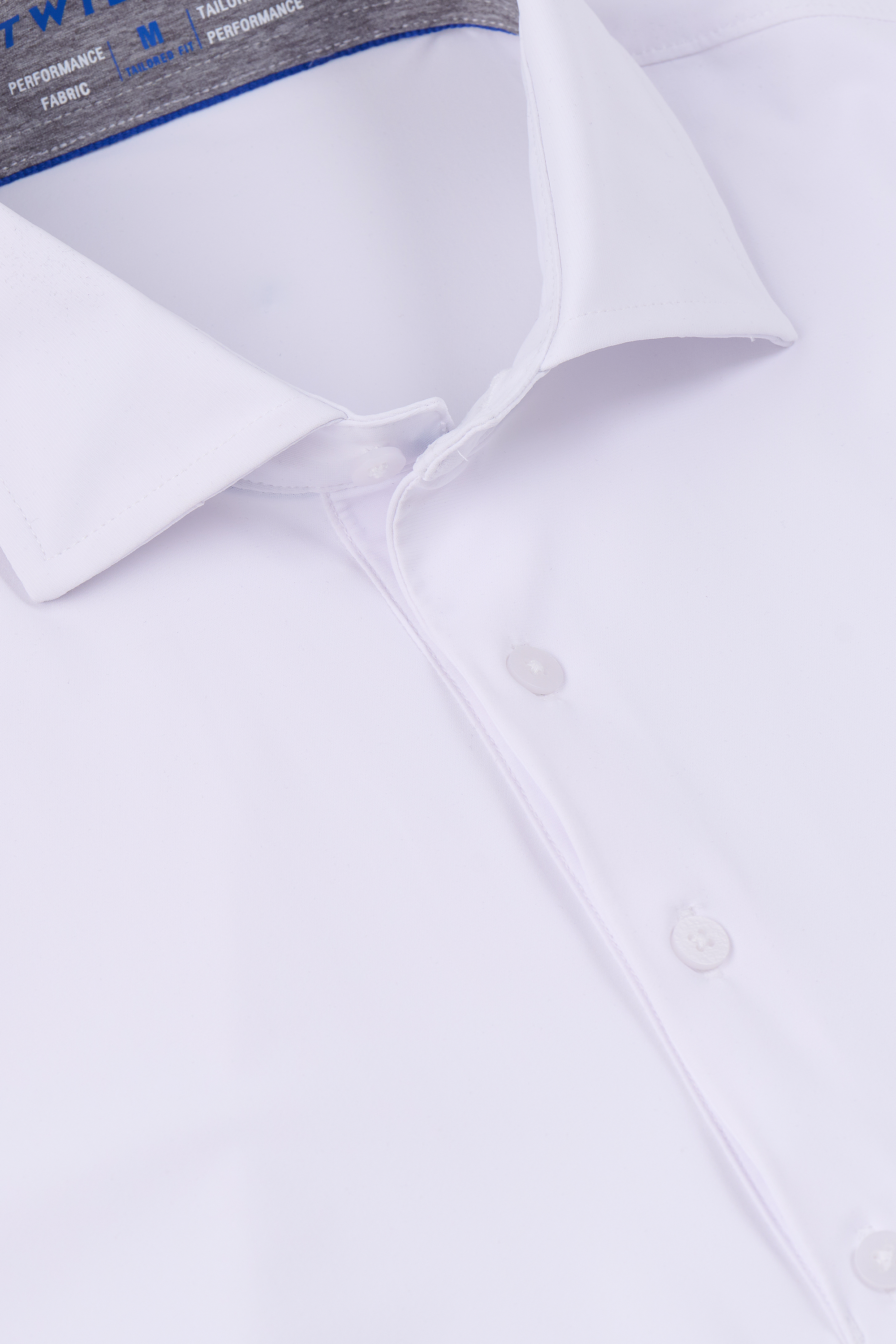 A close-up of Twillory's Event Polo Solid in white, neatly folded to showcase its crisp collar, buttons, and stretchy wrinkle-free fabric. The smooth, clean finish highlights the label text inside the collar.