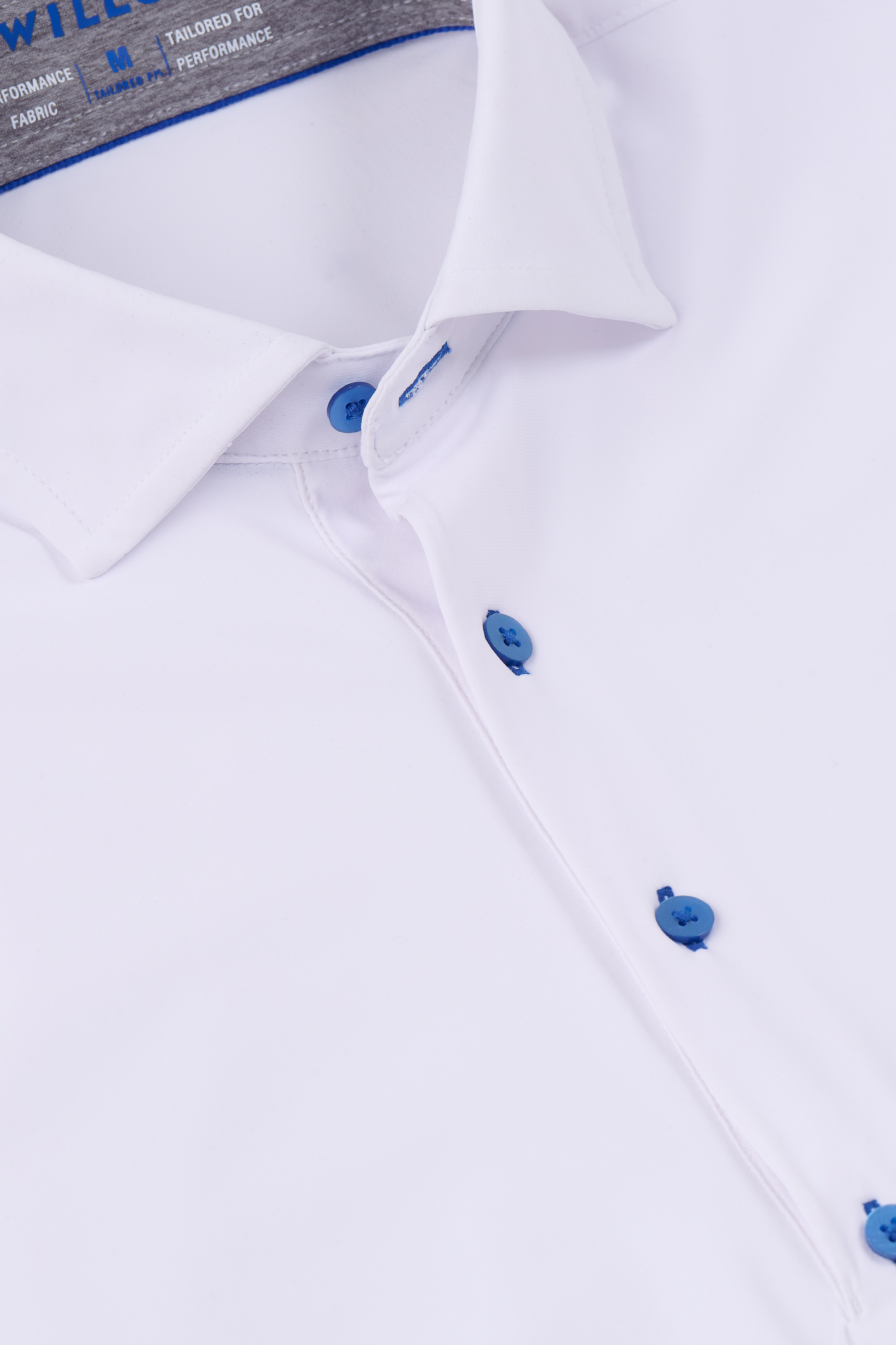 Close-up of the Twillory Event Polo Contrast // White Blue. The image highlights the white collar with blue buttons, placket, medium label, and visible stitching on wrinkle-free performance fabric for a smooth, fitted look.