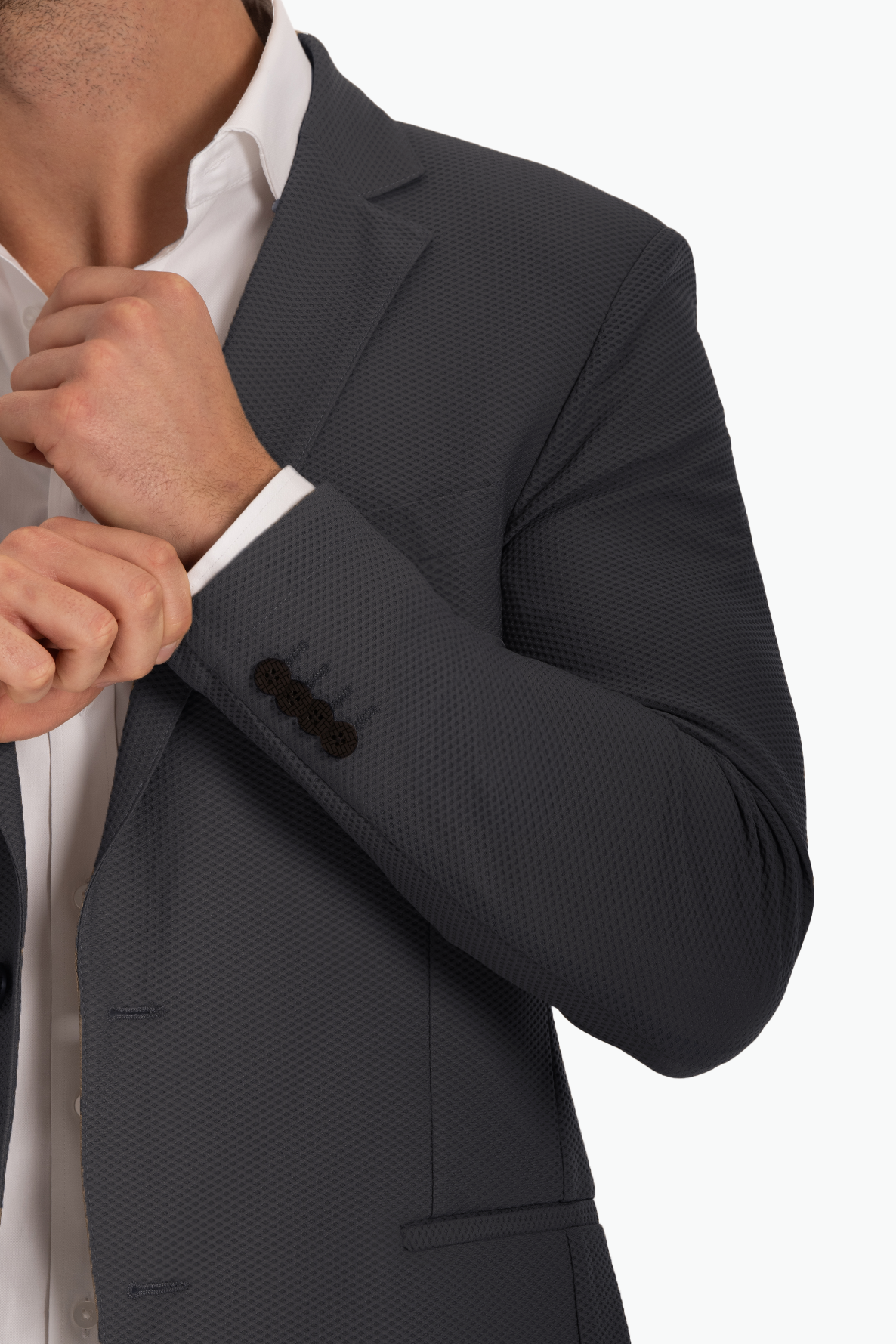 Man adjusting cuff of a tailored charcoal suit jacket with a white shirt.