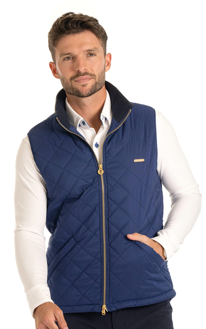 Man wearing a blue quilted vest with a gold zipper and white shirt, posing against a white background.