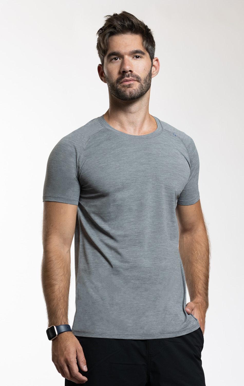 A man in a gray t-shirt standing against a plain white background.