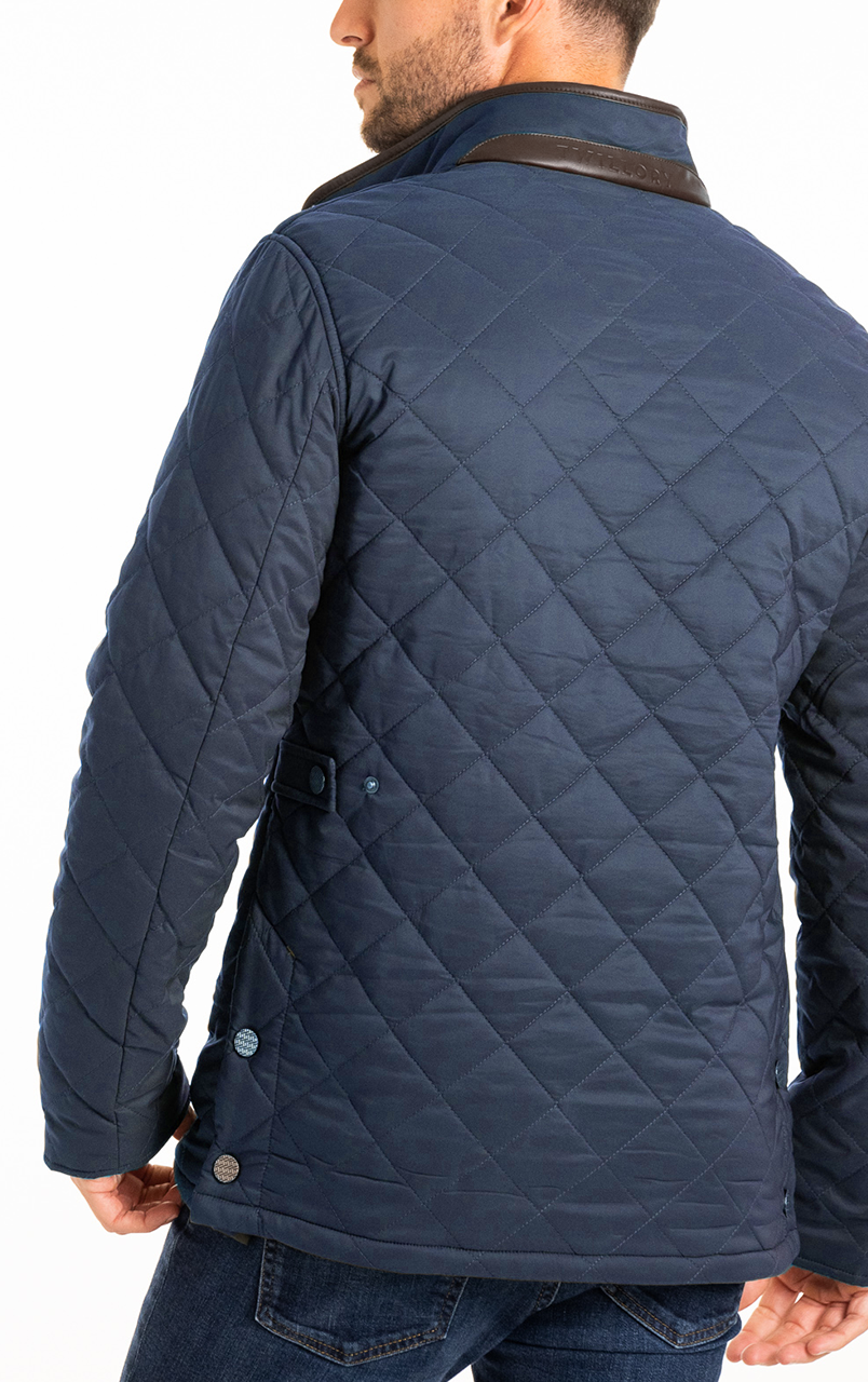 Man wearing a navy blue quilted jacket with leather collar detail, viewed from the back.