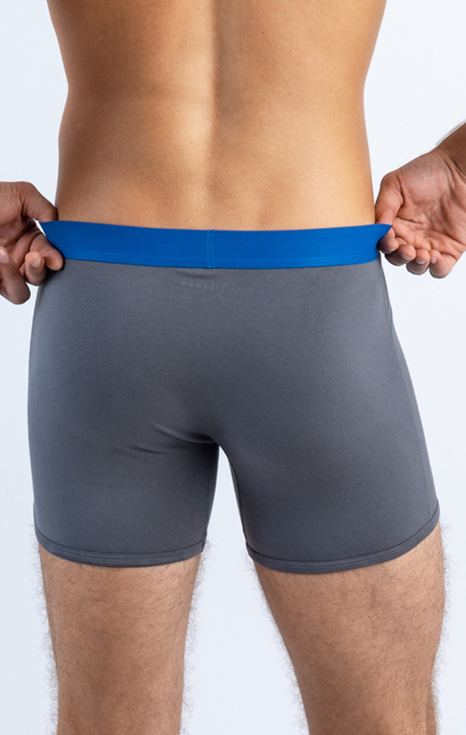A person wearing gray boxer briefs with a blue waistband, viewed from behind.