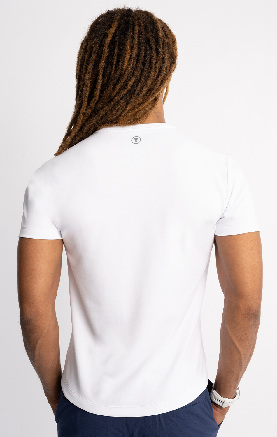 Man with dreadlocks wearing a white T-shirt viewed from the back.